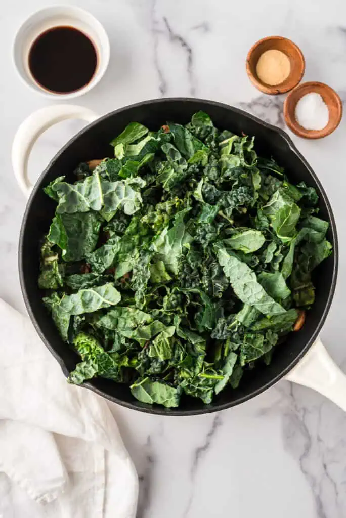Chopped kale added to skillet with sauteed mushrooms.