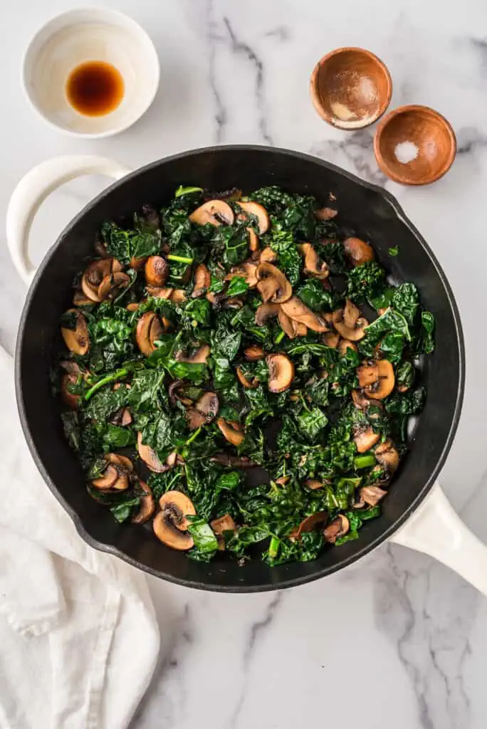 Sautéed kale and mushrooms in a cast iron skillet.