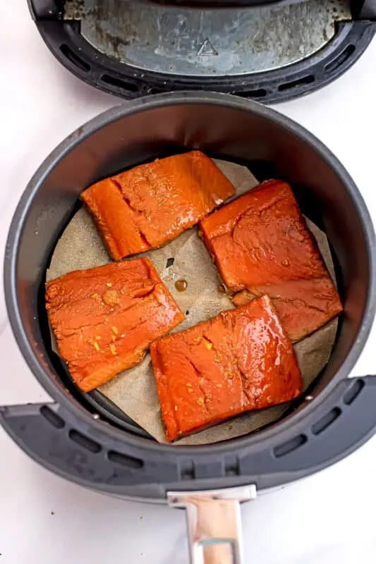 Raw teriyaki salmon in air fryer basket.