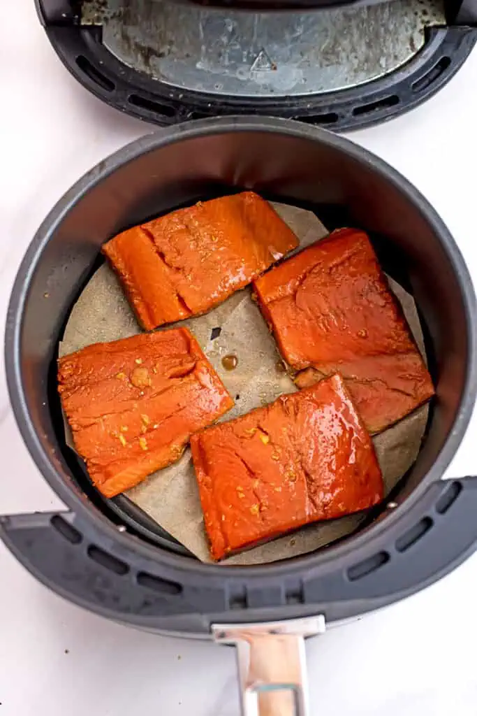 Raw teriyaki salmon in air fryer basket. 