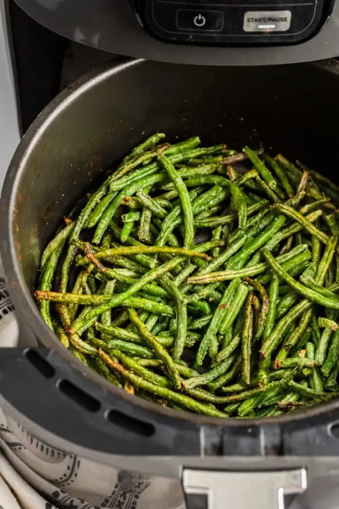 Frozen green beans cooked in the air fryer basket.