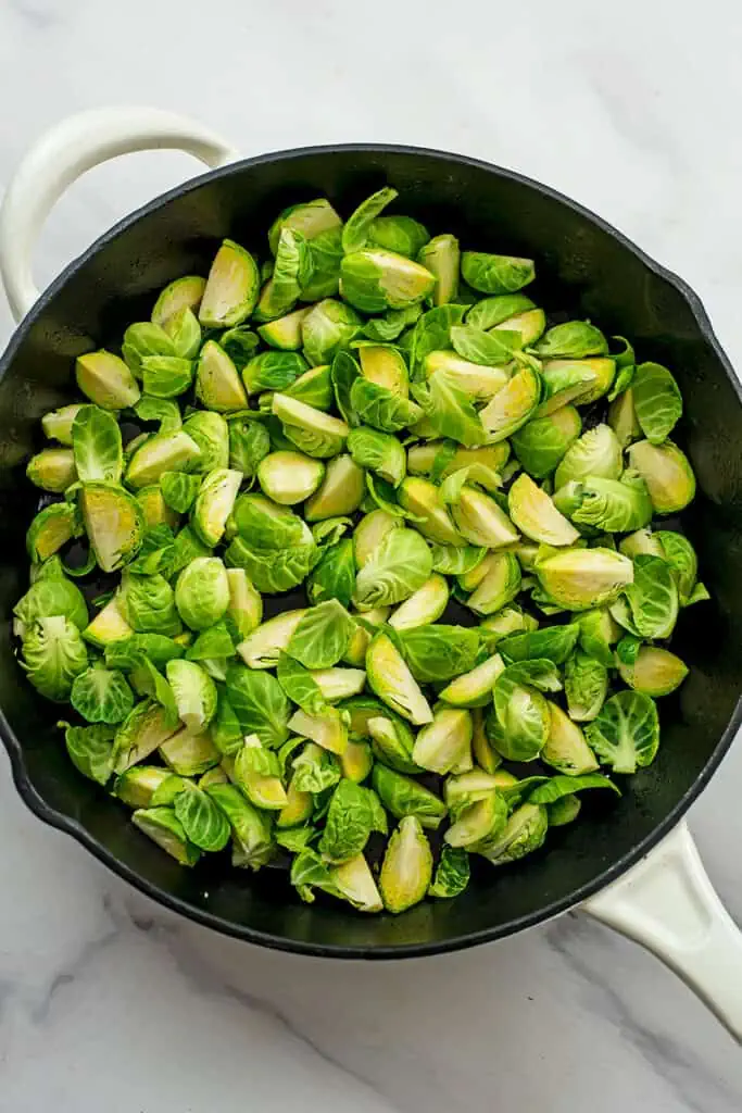 Brussel sprouts quartered in a cast iron skillet. 
