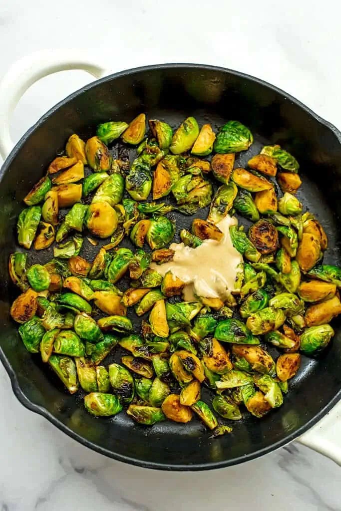 Tahini added to brussel sprouts in cast iron skillet.