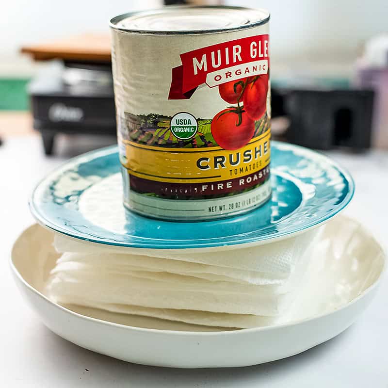 Can of tomato sauce weighing down tofu to press out the liquid.