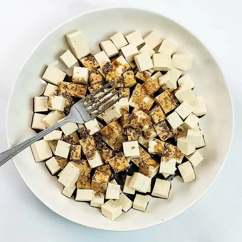 Tofu in a bowl with balsamic marinade poured over the top.