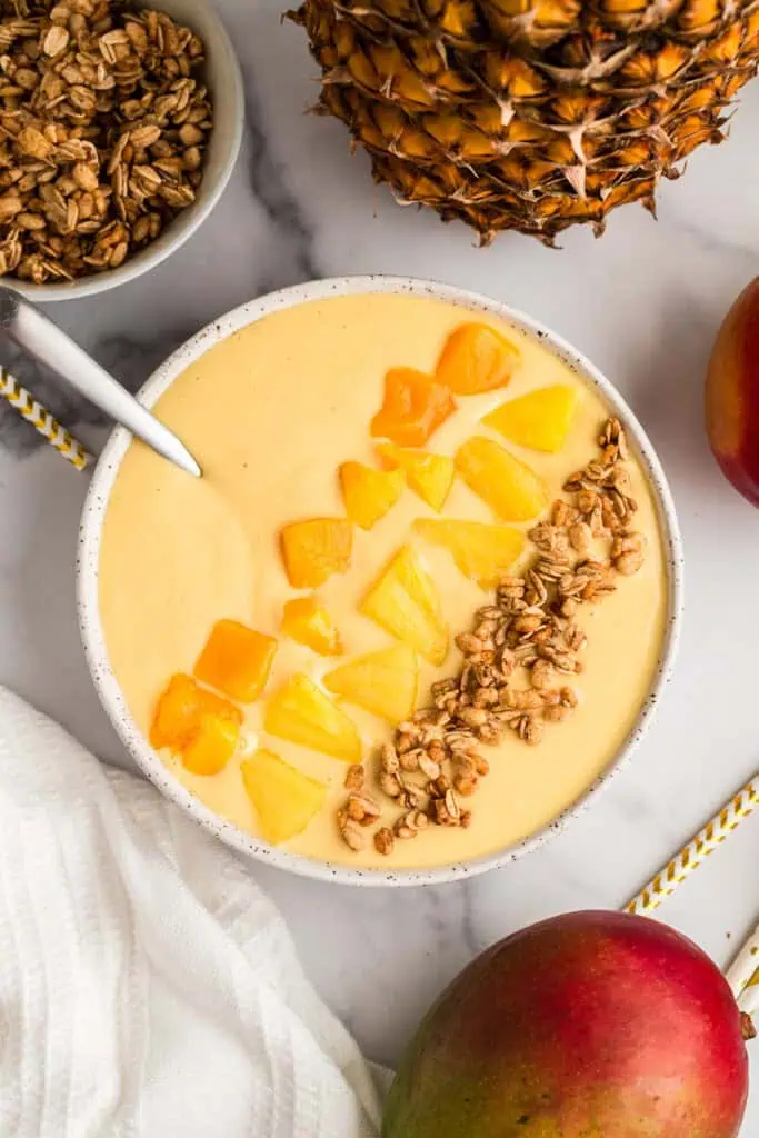 Mango pineapple smoothie bowl with a spoon resting in the bowl.