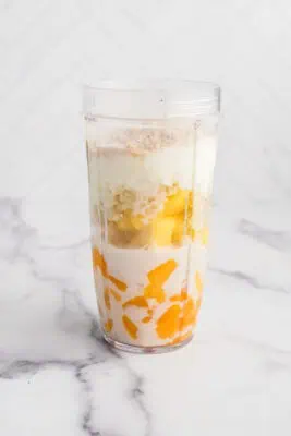 Pineapple mango smoothie in blender before blending.