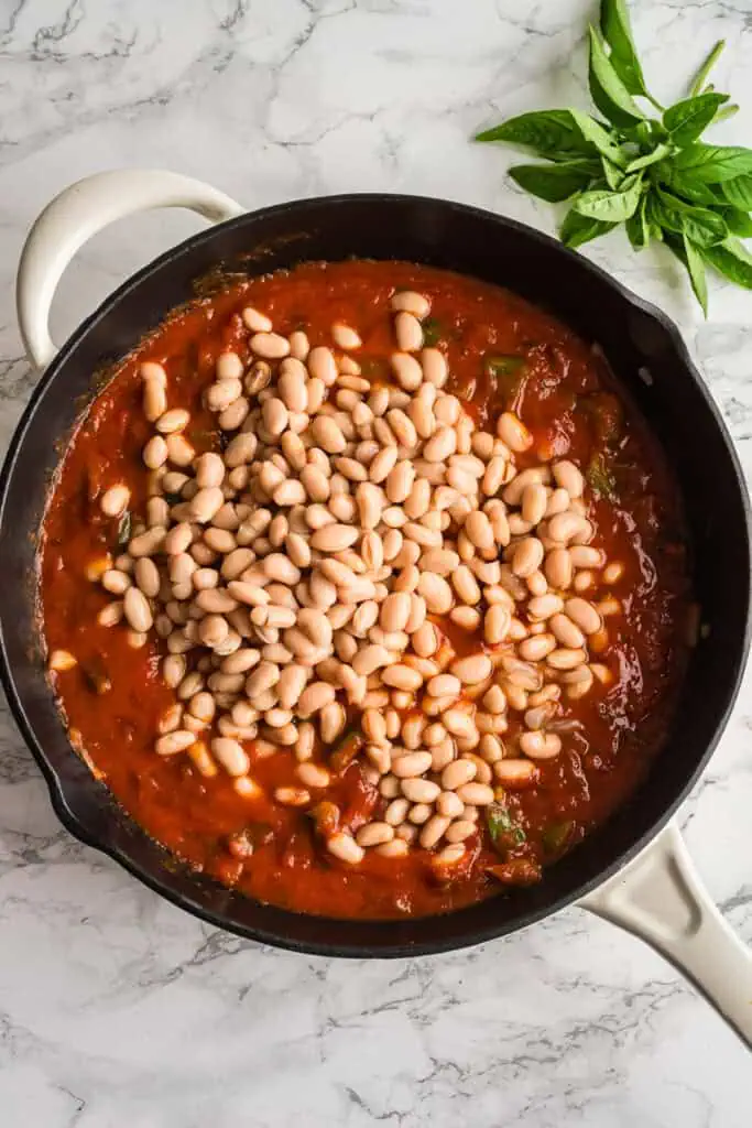 White beans added to marinara and veggies in cast iron skillet.