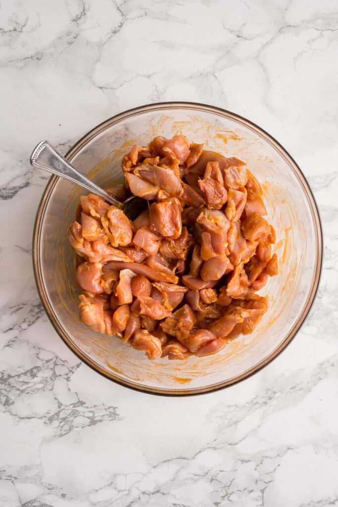 Chicken pieces with buffalo sauce in a glass bowl.