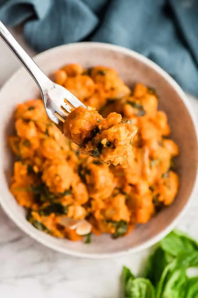 Forkful of gnocchi with tomato sauce over the bowl.