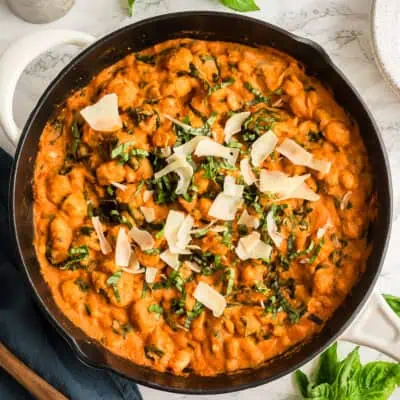 Gnocchi with tomato sauce in a large skillet with parmesan cheese on top.