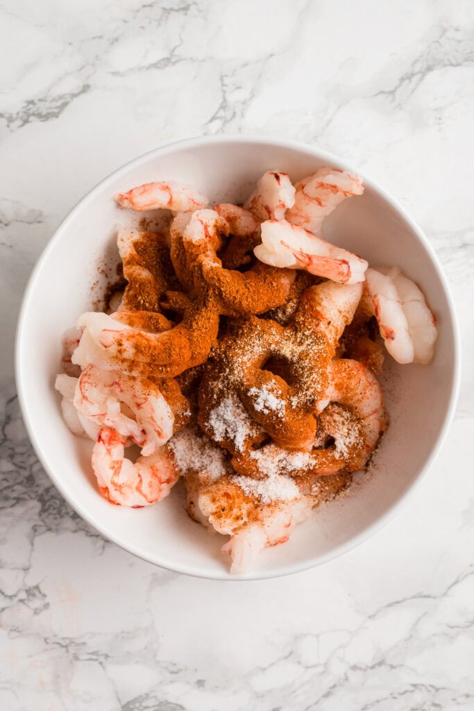 Shrimp in a bowl with blackening seasoning.