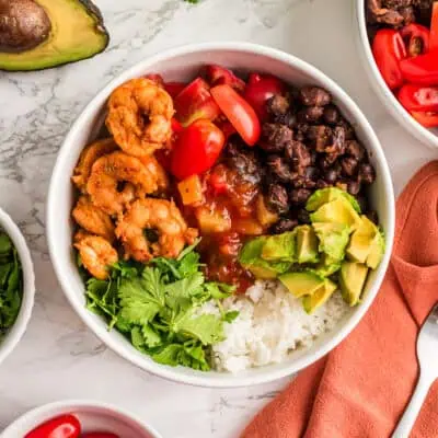 Blackened shrimp rice bowl with avocado, tomato, black beans and cilantro.