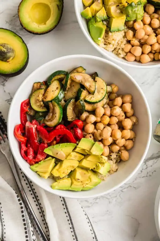 Green Goddess bowl with quinoa, avocado, chickpeas, zucchini and roasted red peppers in a bowl.