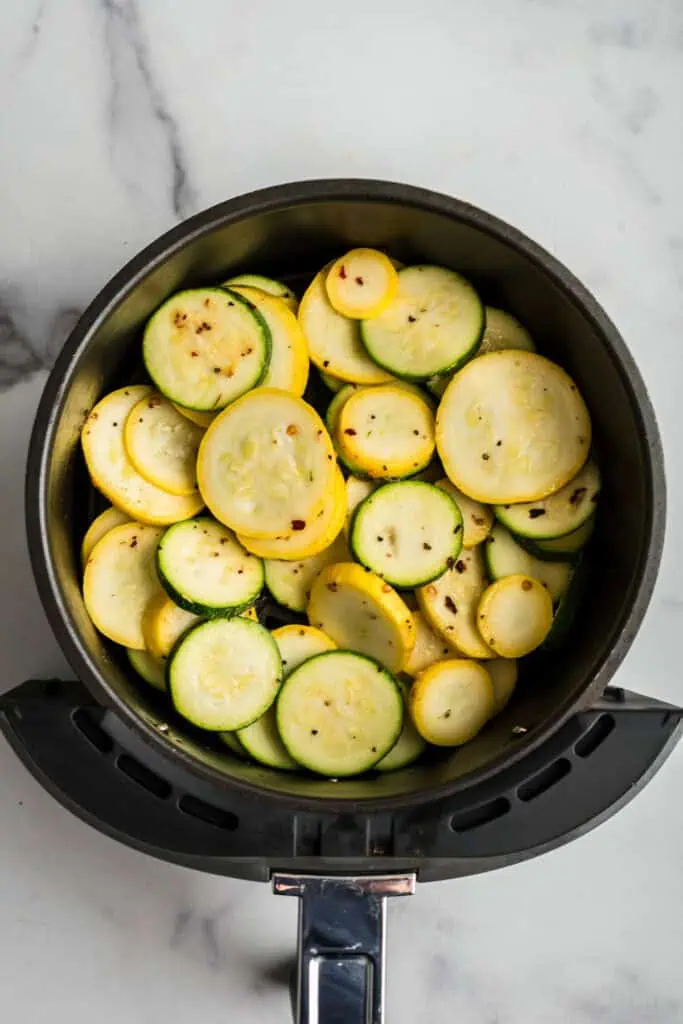 Sliced squash in air fryer before cooking.