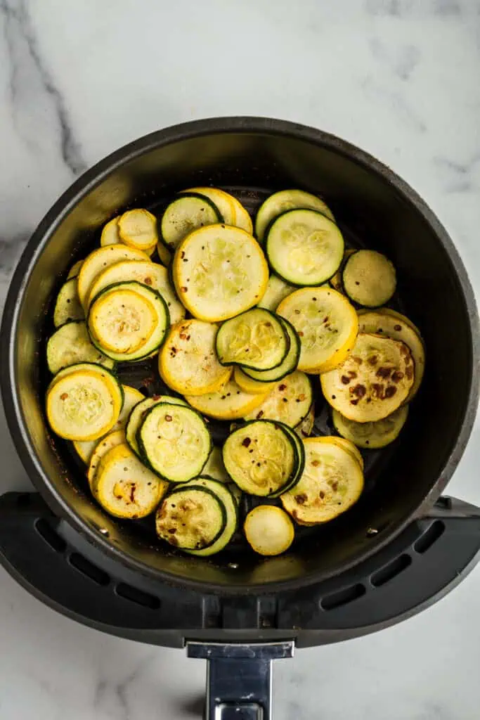 Sliced squash in the air fryer after cooking.