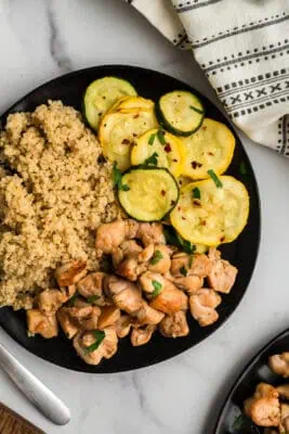 Italian cubed chicken with air fryer squash and quinoa on a black plate.