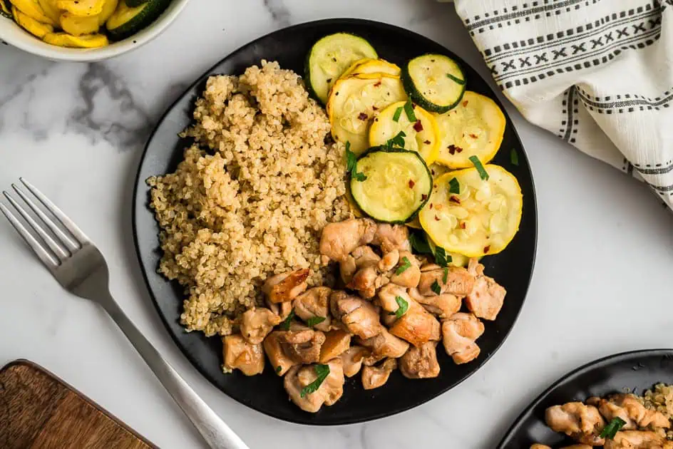 Italian chicken, air fryer squash and quinoa on a black plate with fork.