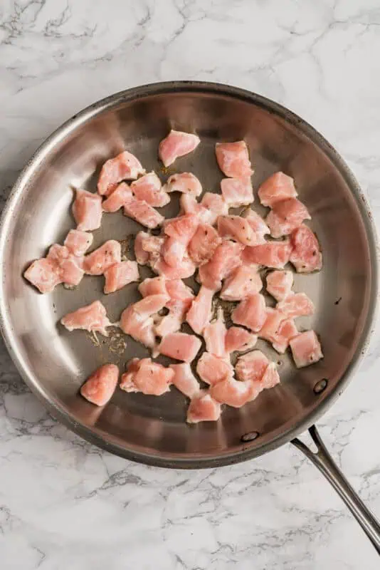 Greek chicken bites in skillet before cooking.