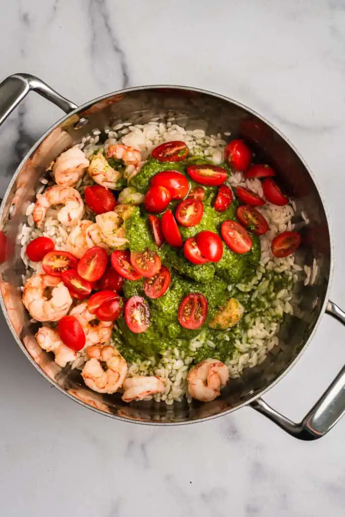 Ingredients to make shrimp orzo pesto in a stainless steel pot before stirring.