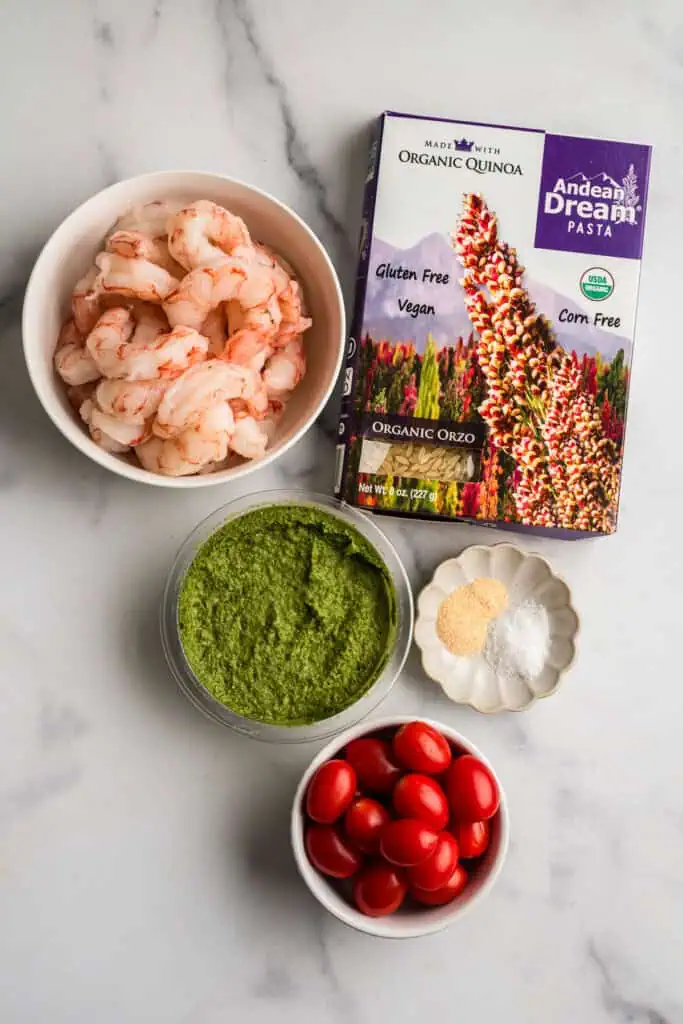 Ingredients to make pesto orzo shrimp on marble countertop.