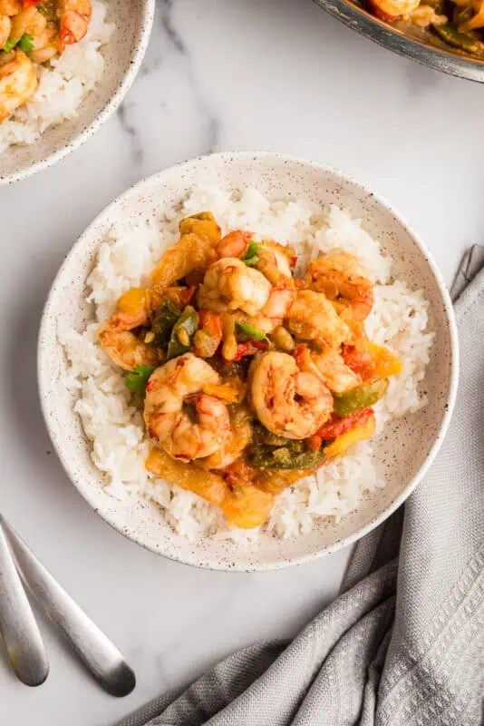 Salsa verde shrimp and rice on a plate with a grey napkin on the side.