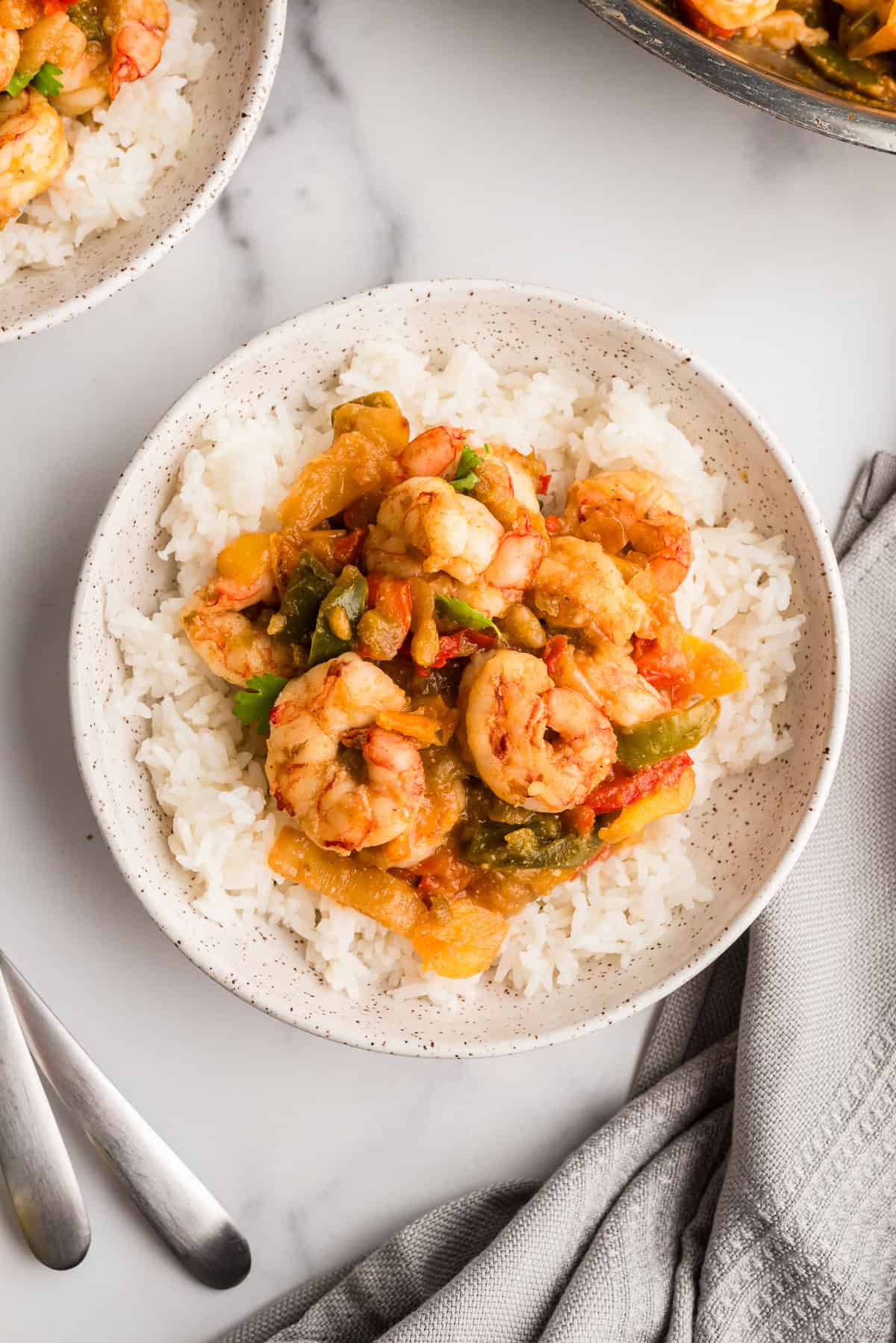 Salsa verde shrimp and rice on a plate with a grey napkin on the side.