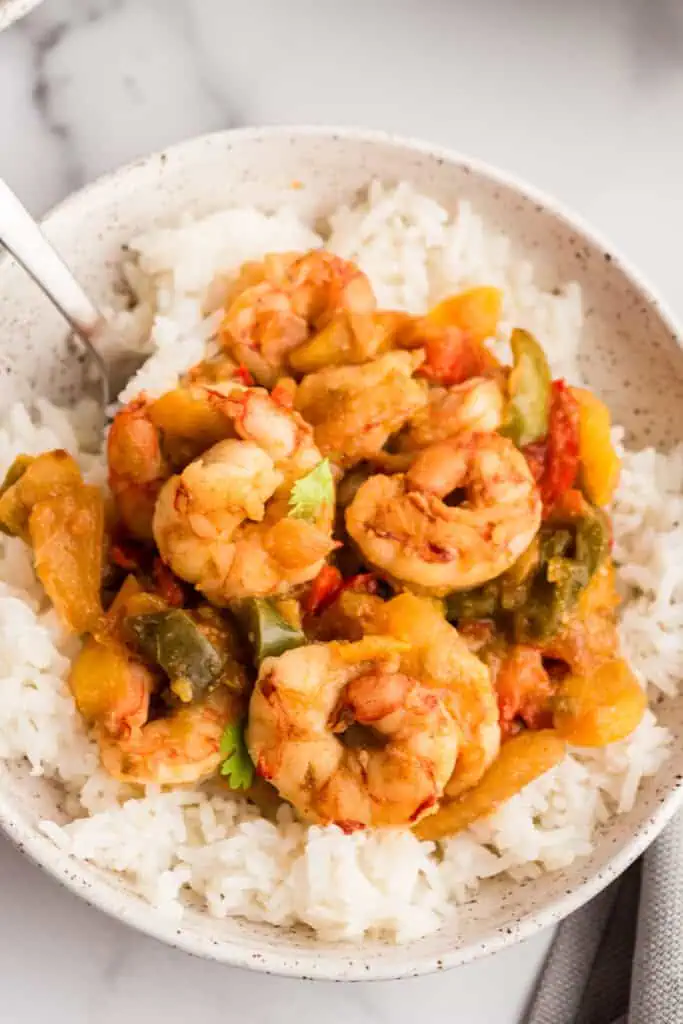 Fork lifting a shrimp out of a bowl of salsa verde shrimp.