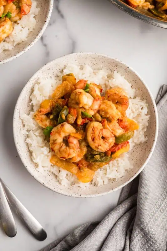 Rice and salsa verde shrimp on a white plate.