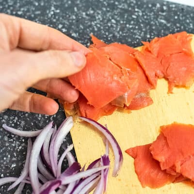 Smoked salmon cut into squares being picked up.