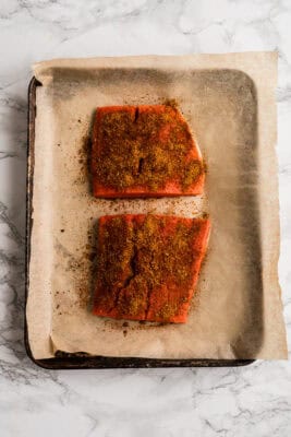 Two pieces of salmon coated in chipotle taco seasoning before cooking.