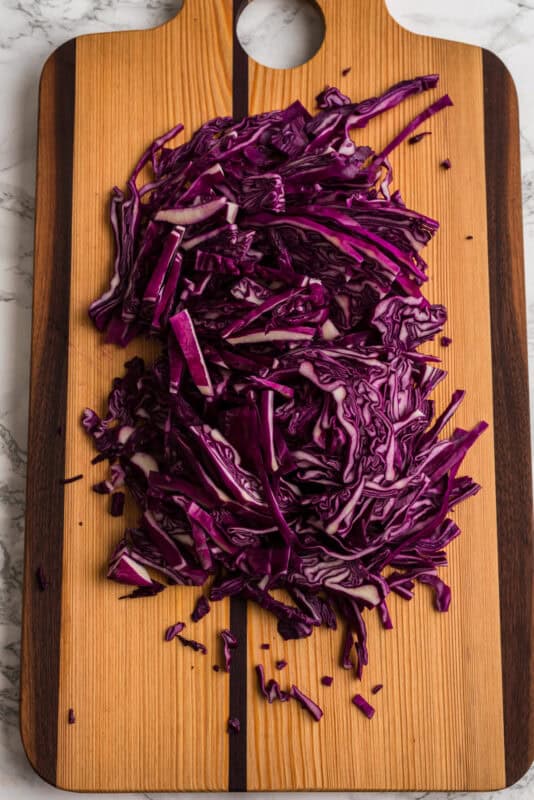 Red cabbage sliced thin on a cutting board.