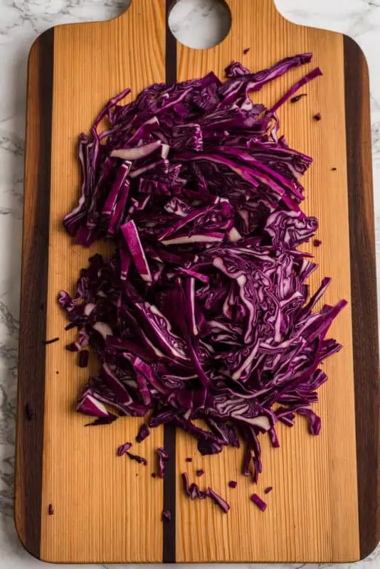 Red cabbage sliced thin on a cutting board.