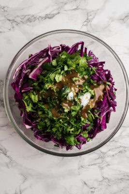 Shredded red cabbage, cilantro and spices in a glass bowl.