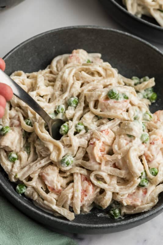 Fork in a bowl filled with cottage cheese shrimp alfredo.