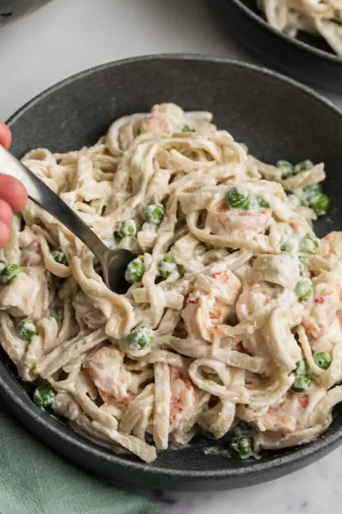Fork in a bowl filled with cottage cheese shrimp alfredo.