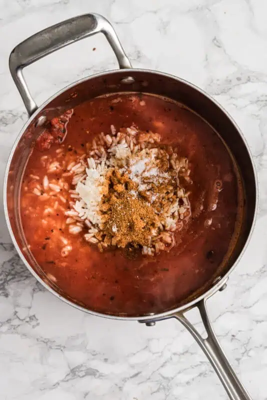 Ingredients to make black bean rice soup in a pot before stirring.