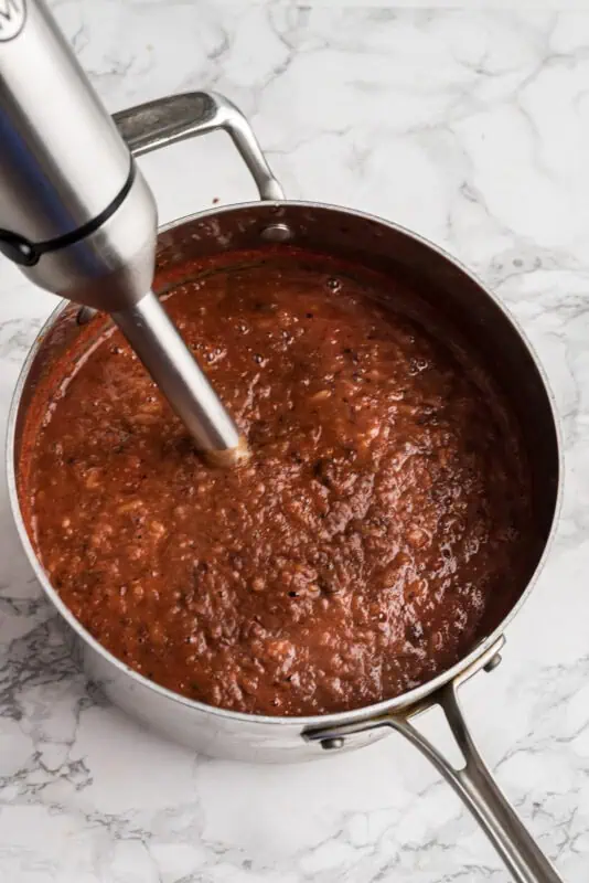 Immersion blender blending up soup in a pot.