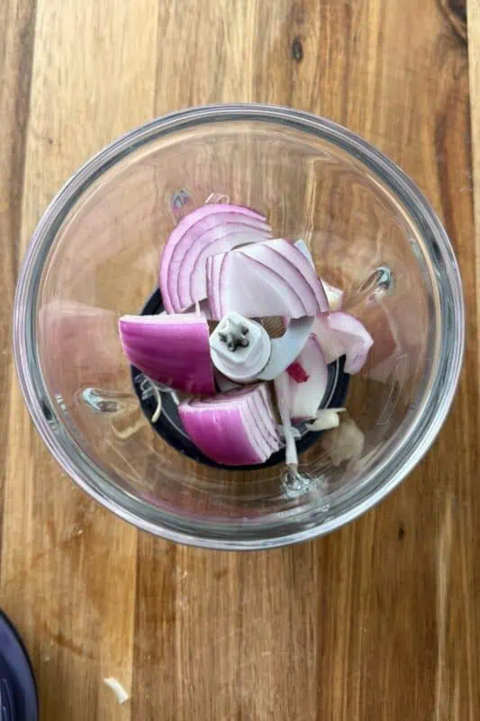 Red onions in a food processor before chopping.