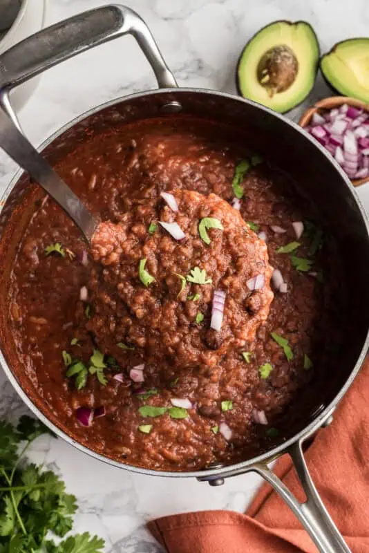 Black bean and rice soup being lifted out of the pot.