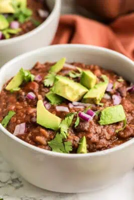 Bowl filled with Mexican black bean rice soup with avocado and cilantro on top.