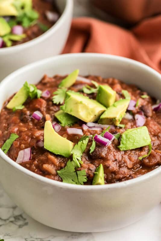 Bowl filled with Mexican black bean rice soup with avocado and cilantro on top.