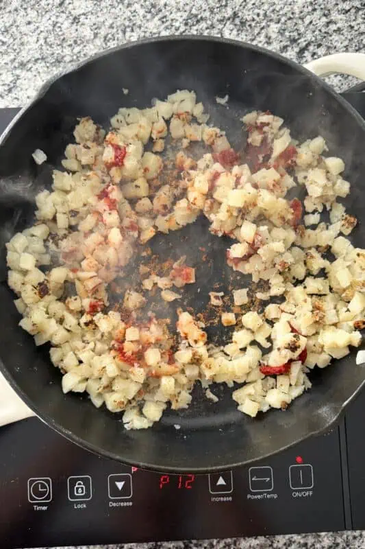 Cooked frozen potatoes in cast iron skillet with tomato paste.
