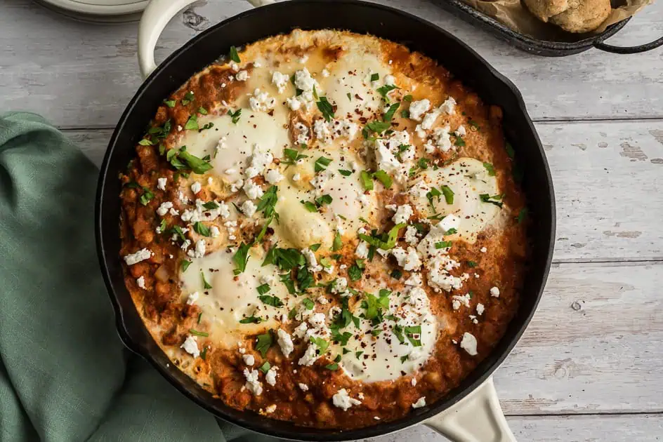 Shakshuka with potatoes and chickpeas in a cast iron skillet. 