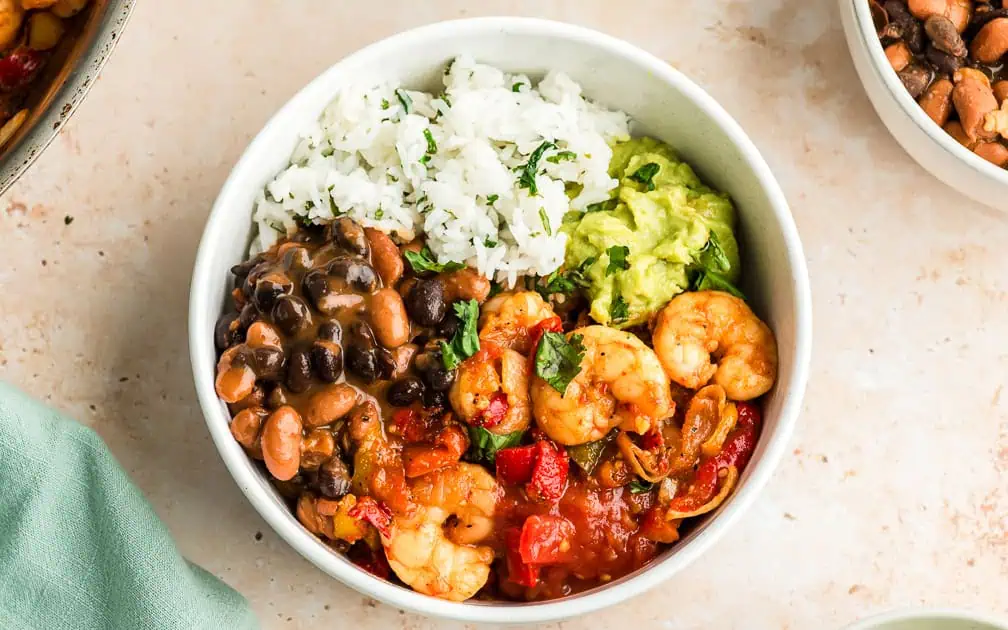 Shrimp burrito bowls in a white bowl with a green napkin to the side.