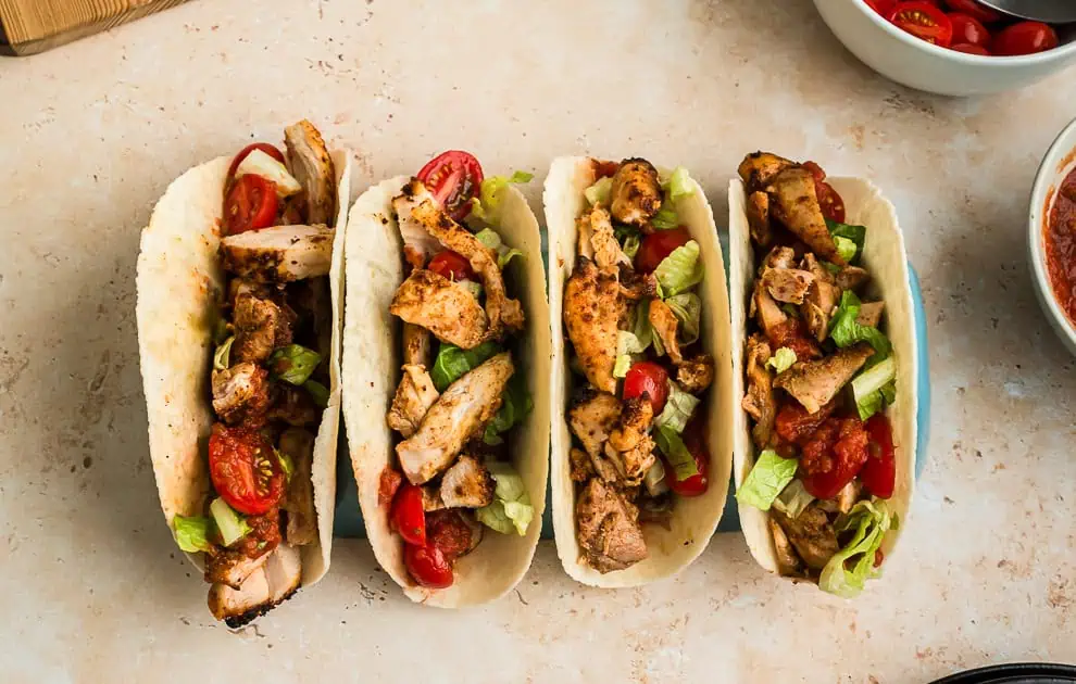 Four air fryer chicken tacos stacked side to side. 