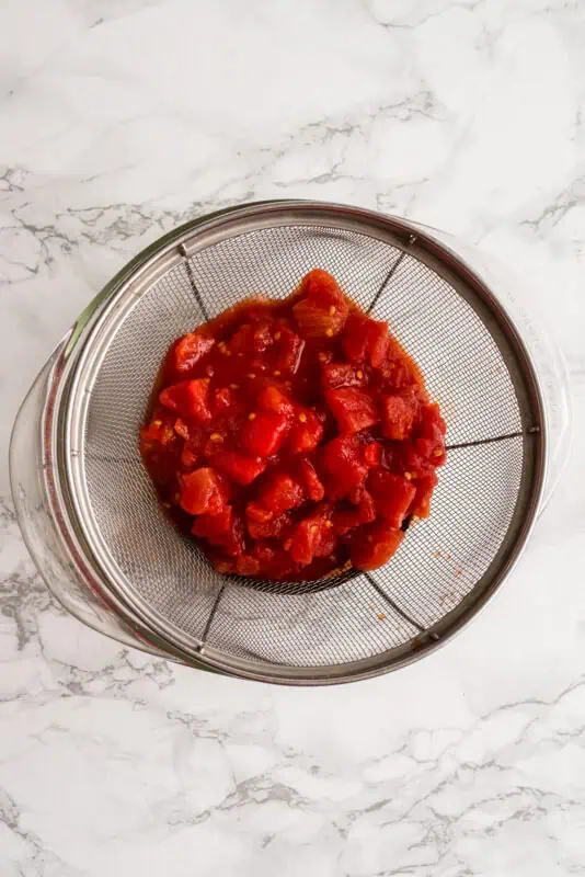 Diced tomatoes in a mesh strainer.