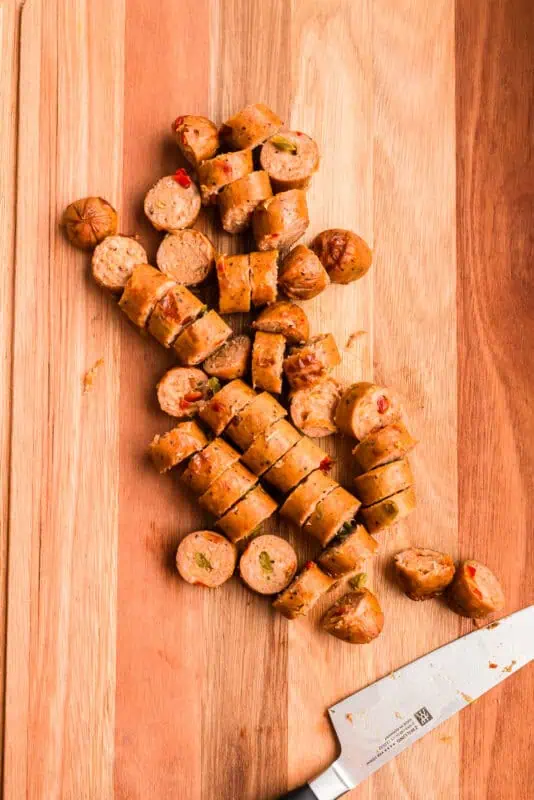 Chicken sausage cut into coins on wood cutting board.