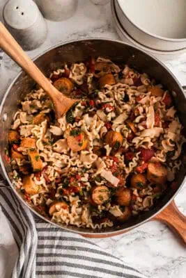 Spoon resting in a pot of italian chicken sausage pasta.