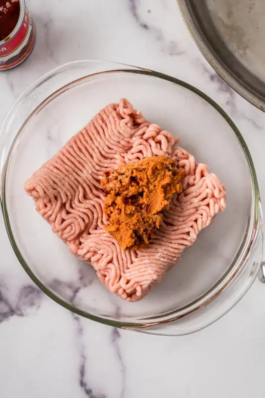 Ground chicken in a glass bowl with the chipotle mixture on top.